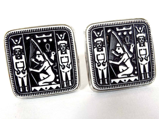 Front view of the Mid Century vintage Dante Egyptian Revival cufflnks. They are rounded square in shape with silver tone color metal. The front cabs are black with a white hieroglyphic style design. 