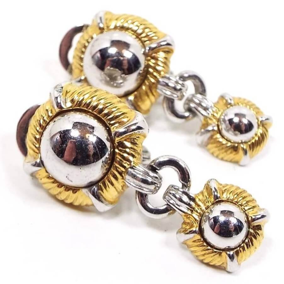 Front view of the retro vintage Monet drop earrings. They have silver tone color round dome areas surrounded by gold tone textured rings around the edge. You can see my reflection in the silver tone taking the photos.