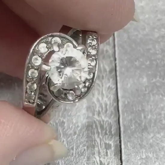 Video of the retro vintage sterling silver cocktail ring. The top of the ring has a curved S like shape with small round CZ stones on it. There is a larger cubic zirconia stone in the middle at the top of the ring. The video shows how the stones sparkle.