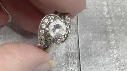 Video of the retro vintage sterling silver cocktail ring. The top of the ring has a curved S like shape with small round CZ stones on it. There is a larger cubic zirconia stone in the middle at the top of the ring. The video shows how the stones sparkle.