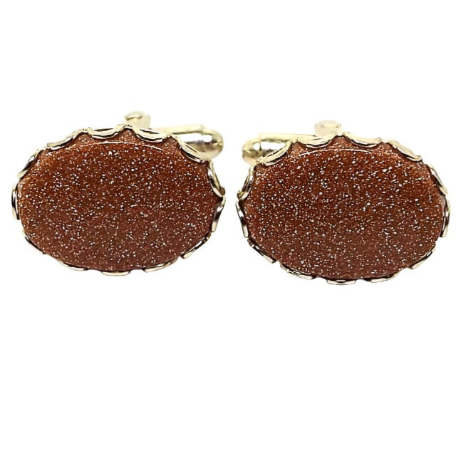 Front view of the Mid Century vintage goldstone cufflinks. They are oval in shape with a gold tone metal color. There are goldstone bezel set cabs on the front that are orange in color with sparkly flecks of copper.