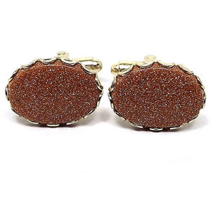 Front view of the Mid Century vintage goldstone cufflinks. They are oval in shape with a gold tone metal color. There are goldstone bezel set cabs on the front that are orange in color with sparkly flecks of copper.