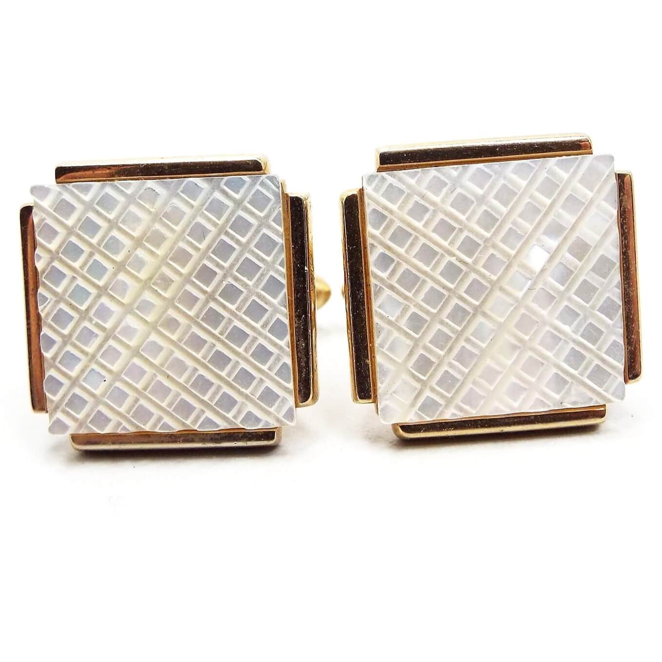 Front view of the Swank Mid Century vintage mother of pearl cufflinks. They are square in shape with bars of gold tone color metal on each side. The middle has a square pearly white mother of pearl shell cab that is carved with a small diamond shape pattern.