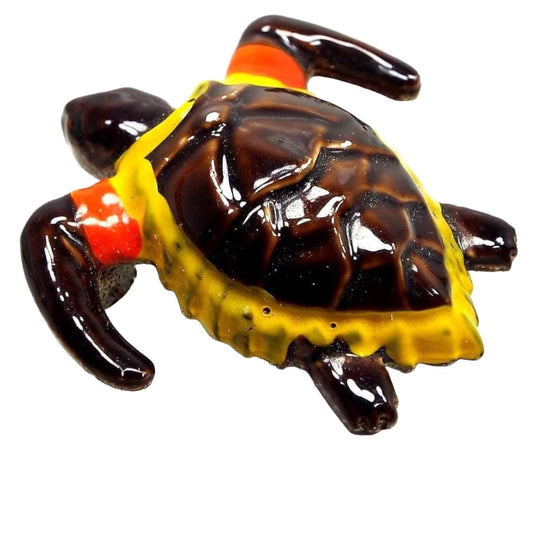 Front view of the Mid Century vintage enameled turtle brooch pin. The head, legs, and main part of the shell are dark brown in color. The edge of the shell is yellow and there are orange bands by the front legs. The head is jointed so it can move from side to side.
