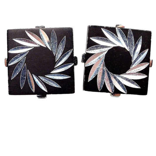 Front view of the retro vintage Swank etched cufflinks. They are square in shape and painted black. There is a pinwheel style design with etched marquis shapes cut on the front in a angled circle pattern.