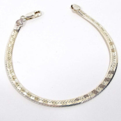 Top view of the retro vintage Italian sterling silver herringbone chain bracelet. The side showing has a diagonal pattern design on the links. It has a lobster claw clasp at the end.
