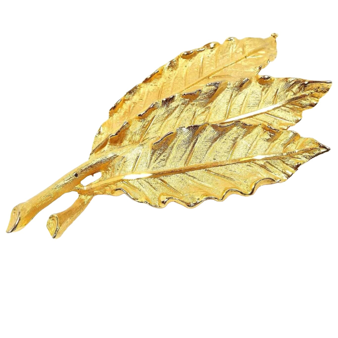 Front view of the retro vintage Coro leaf brooch pin. The metal is matte textured gold tone color. There brooch has three detailed leaves in a bunch.