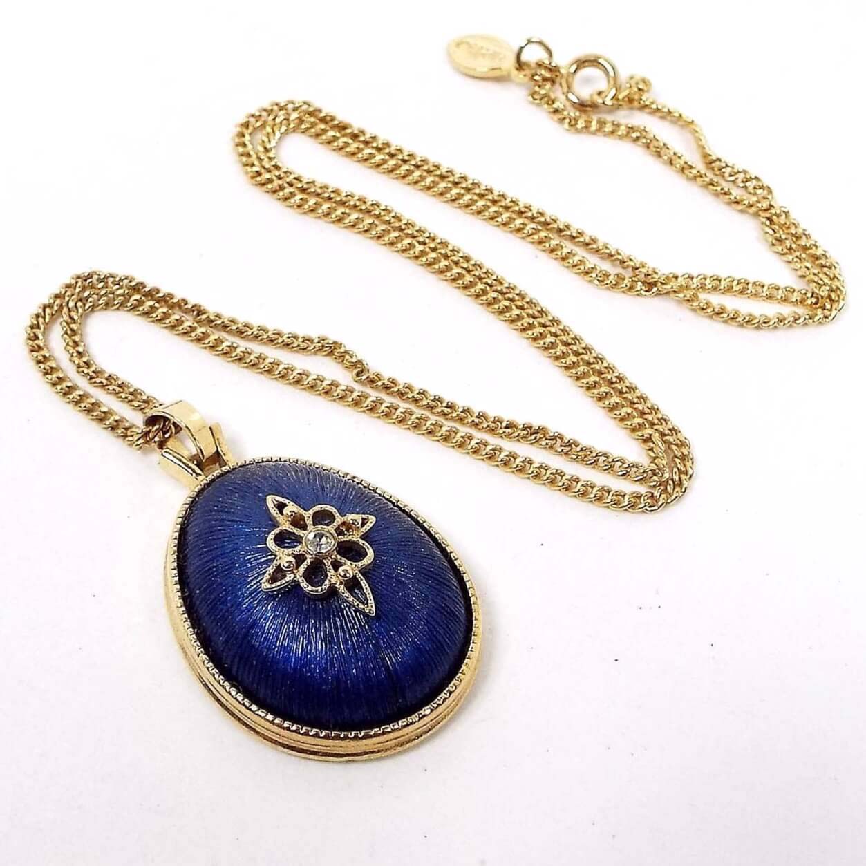 Front view of the retro vintage Avon pendant necklace. The metal is gold tone in color. The pendant is tear drop shaped with blue plastic cab and a rhinestone in the middle of a gold tone star shape. 