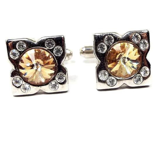 Front view of the retro vintage rhinestone cufflinks. They are silver tone in color. There is a rivoli round rhinestone in the middle that's peach in color and two small round clear rhinestones at each corner.