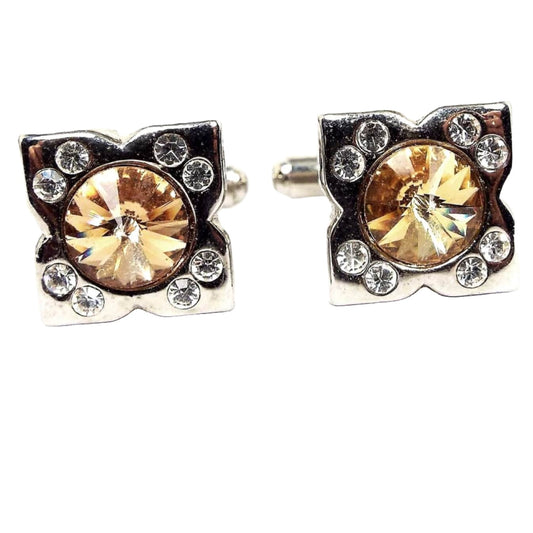 Front view of the retro vintage rhinestone cufflinks. They are silver tone in color. There is a rivoli round rhinestone in the middle that's peach in color and two small round clear rhinestones at each corner.