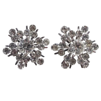 Front view of the Mid Century vintage Coro screw back earrings. The metal is silver tone in color. They  have a starburst shape with round prong set clear rhinestones in different sizes. 