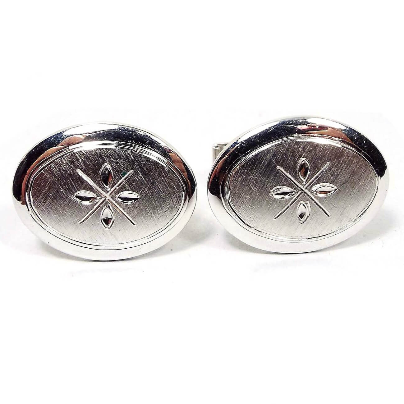 Front view of the Mid Century vintage sterling silver cufflinks. they are oval with matte brushed fronts and an etched design in the middle that looks like an X with marquis shapes in between each set of lines.