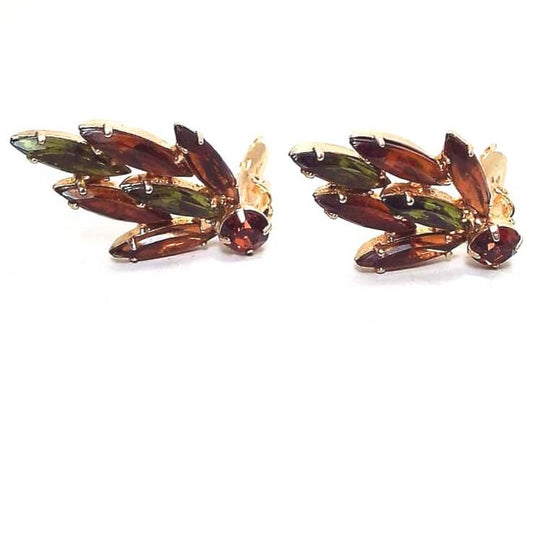 Front view of the Mid Century vintage rhinestone earrings. The metal is gold tone in color. There are long marquis shaped rhinestones in orange and green giving a leaf like design and a darker orange round rhinestone at the bottom.