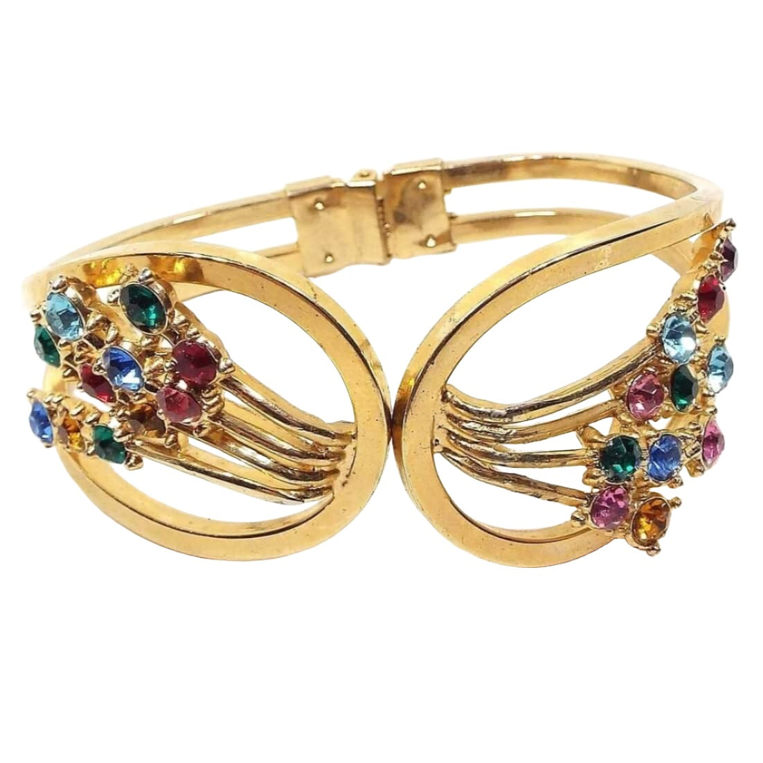 Front view of the Mid Century vintage rhinestone hinged bangle bracelet. The bracelet is gold tone in color and has a clamper style design that opens at the top and is hinged in the back. There are clusters of round rhinestones on each side in shades of green, blue, red, pink, yellow, and orange.