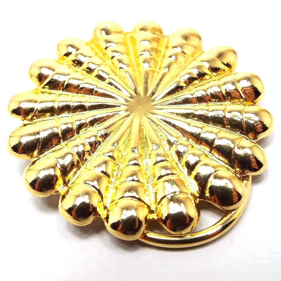 Front view of the retro vintage scarf clip. It is gold tone in color and has a scalloped round style starburst design.