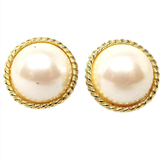 Front view of the retro vintage faux pearl clip on earrings. They are round with off white plastic domed imitation pearl fronts. There is a  gold tone color metal twisted rope design around the edge.