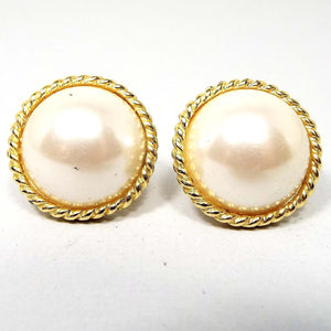Front view of the retro vintage faux pearl clip on earrings. They are round with off white plastic domed imitation pearl fronts. There is a  gold tone color metal twisted rope design around the edge.