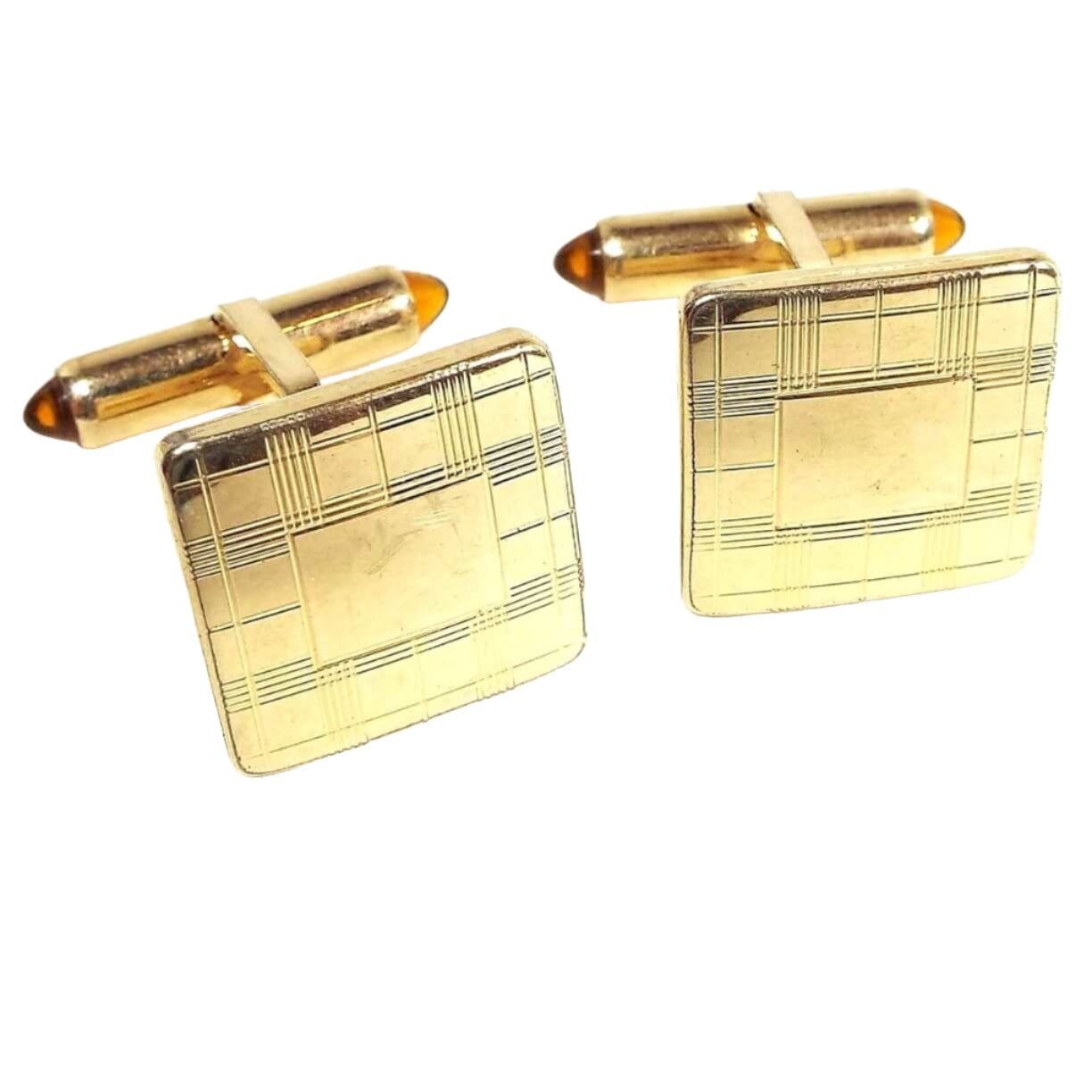 Front view of the Mid Century vintage Krementz cufflinks. They are square and gold tone in color with a lightly etched plaid like pattern on the front. The backs have domed orange lucite caps on each side of the levers.