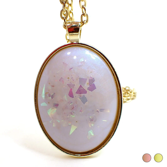 Front view of the large handmade oval resin pendant necklace. The resin has an opal like color shift sheen of blue. There is AB pink chunky glitter embedded in the resin. The setting shown is gold plated color but there are two dots at the bottom right of the photo showing a choice of rose gold plated or gold plated.