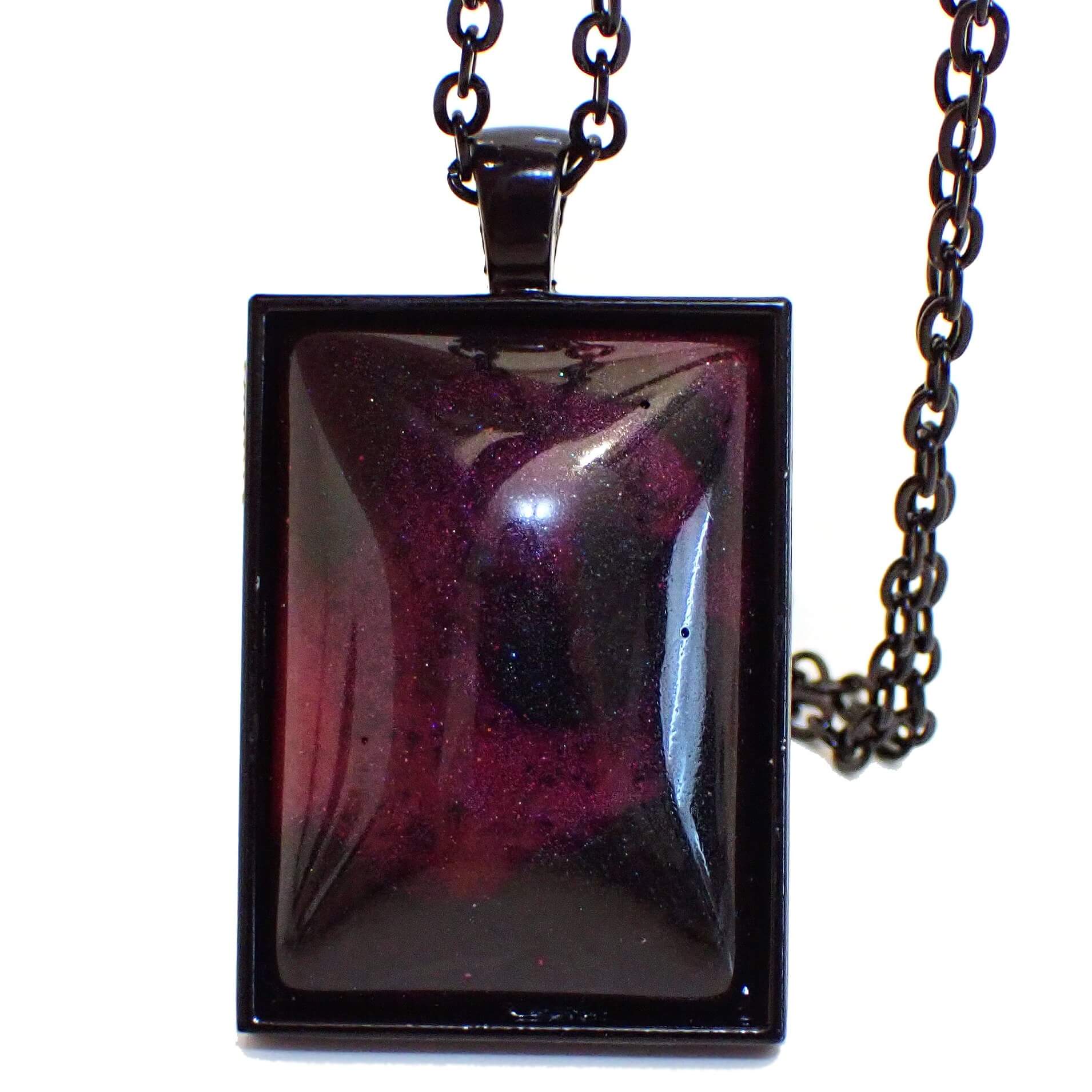 Front view of the handmade Goth resin pendant necklace. The metal is black coated. There is a large rectangle pendant with marbled pearly black, pink, and purple tones in the resin. 