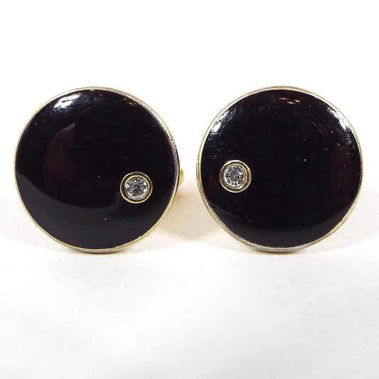 Front view of the retro vintage enameled cufflinks. The fronts are round and black enameled with a small round rhinestone at one edge. 