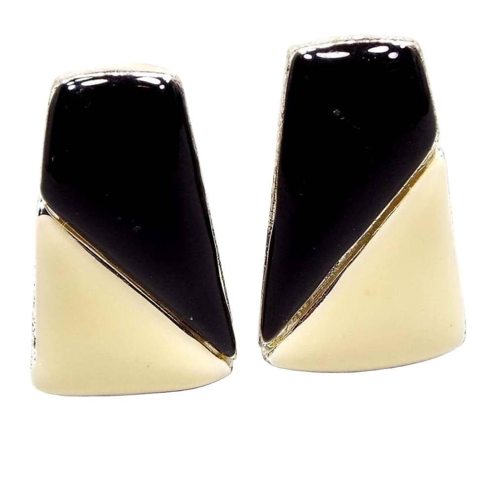 Front view of the retro vintage enameled clip on earrings. They have a geometric trapezoid design with the top angled half enameled in black and the bottom enameled in an off white cream color.