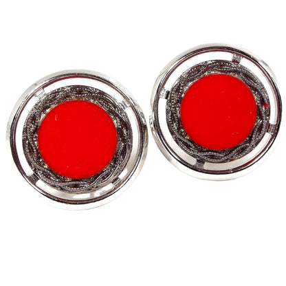 Front view of the Mid Century vintage Hickok cufflinks. They are round and silver tone in color. The middle has bright red glass cabs. There is a tiny chip in one towards the edge when viewed under magnification.