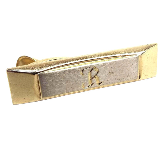 Front view of the Mid Century vintage Hickok tie clip. The front rectangle area of the tie clip is silver tone in color and the rest is gold tone in color. There is a letter R engraved on the front.