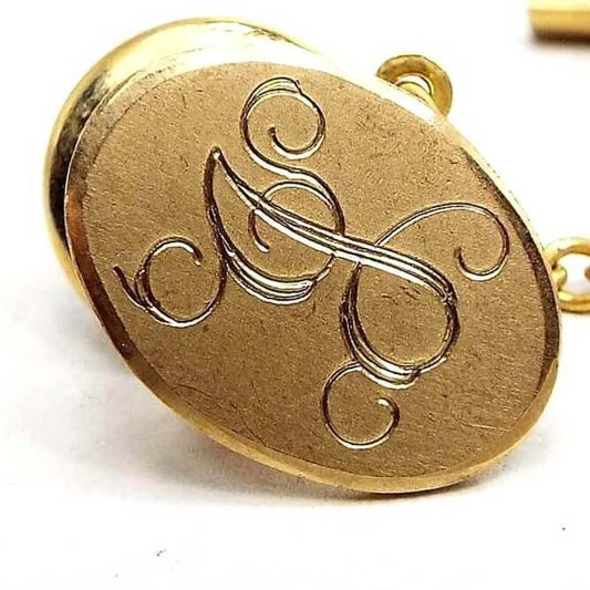 Enlarged front view of the Mid Century vintage initial tie tack. It is a darkened gold tone in color with a fancy script letter J engraved on the front.