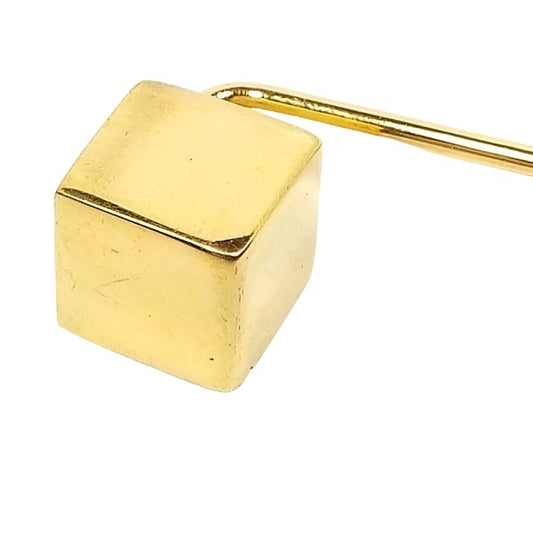 Enlarged view of the retro vintage geometric stick pin. The metal is gold tone in color and there is a cube shape at the top.