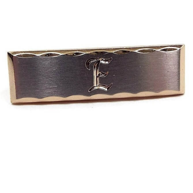 Front view of the Hickok Mid Century vintage initial tie clip. The edge is gold tone in color with a scalloped cut design. The middle part is silver tone in color with the letter E engraved on the front.