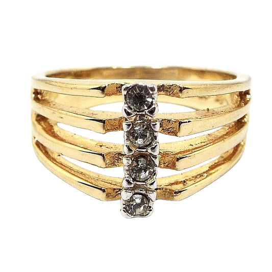 Front view of the retro vintage rhinestone ring. The metal is gold tone in color. The band is split at the sides and top into four band sections. Each one has a small prong set round rhinestone in the middle. 