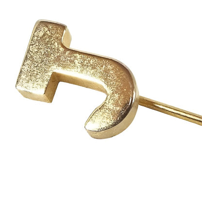 Enlarged view of the top of the Mid Century vintage initial stick pin. The metal is gold tone in color and there is a block style letter J at the top.