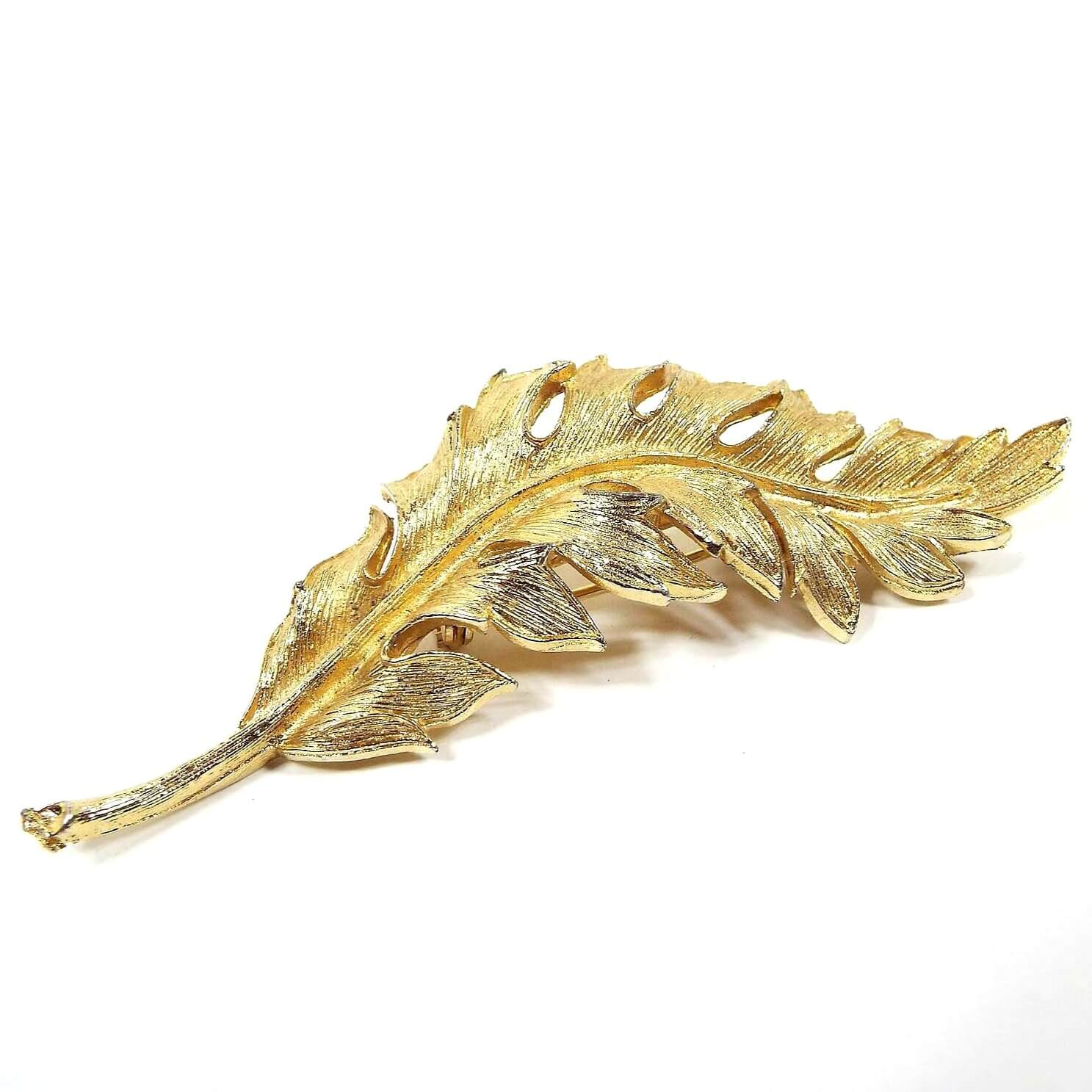 Front view of the 1961 Mid Century vintage Coro leaf brooch pin. It is shaped like a long leaf with stem and is nicely detailed in gold tone color metal. 