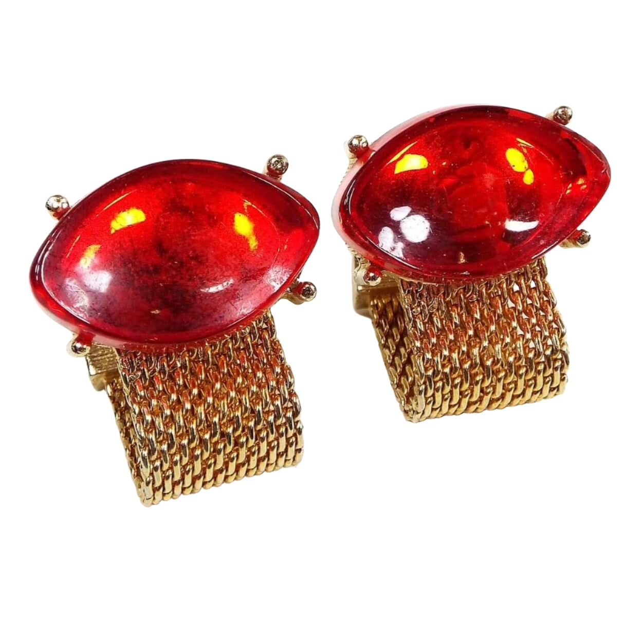 Front view of the Mid Century vintage glass wrap around mesh cufflinks. The metal is gold tone in color. There are large oval red glass cabs at the top and metal mesh straps on the bottom that go around to the back.