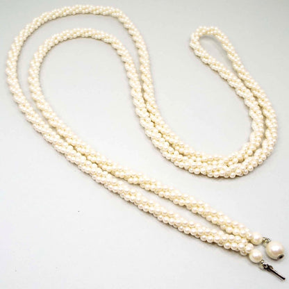 Mid Century vintage faux pearl necklace. It is long with multi strands twisted into a rope like design. The imitation pearls are small, round, and made of plastic. There is a round faux pearl clasp at the end.