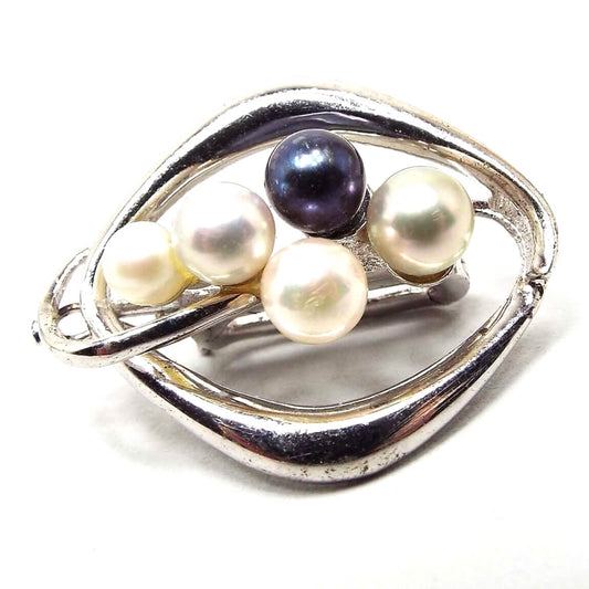 Front view of the 1940's Mid Century vintage ribbon choker pendant slide. It has an open rounded diamond shape with 825 silver that is a slightly darker silver in color. There are five cultured pearls in the middle open area. All are round. They vary in shade from white to off white and one is a darky blue gray in color. 