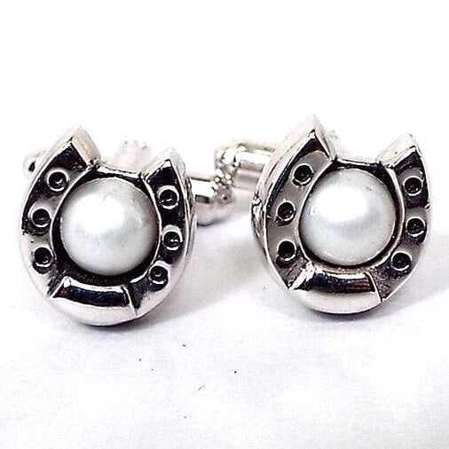 Front view of the Mid Century vintage Hickok cufflinks. They are silver tone in color and shaped like a horseshoe. There are white faux pearls in the middle.