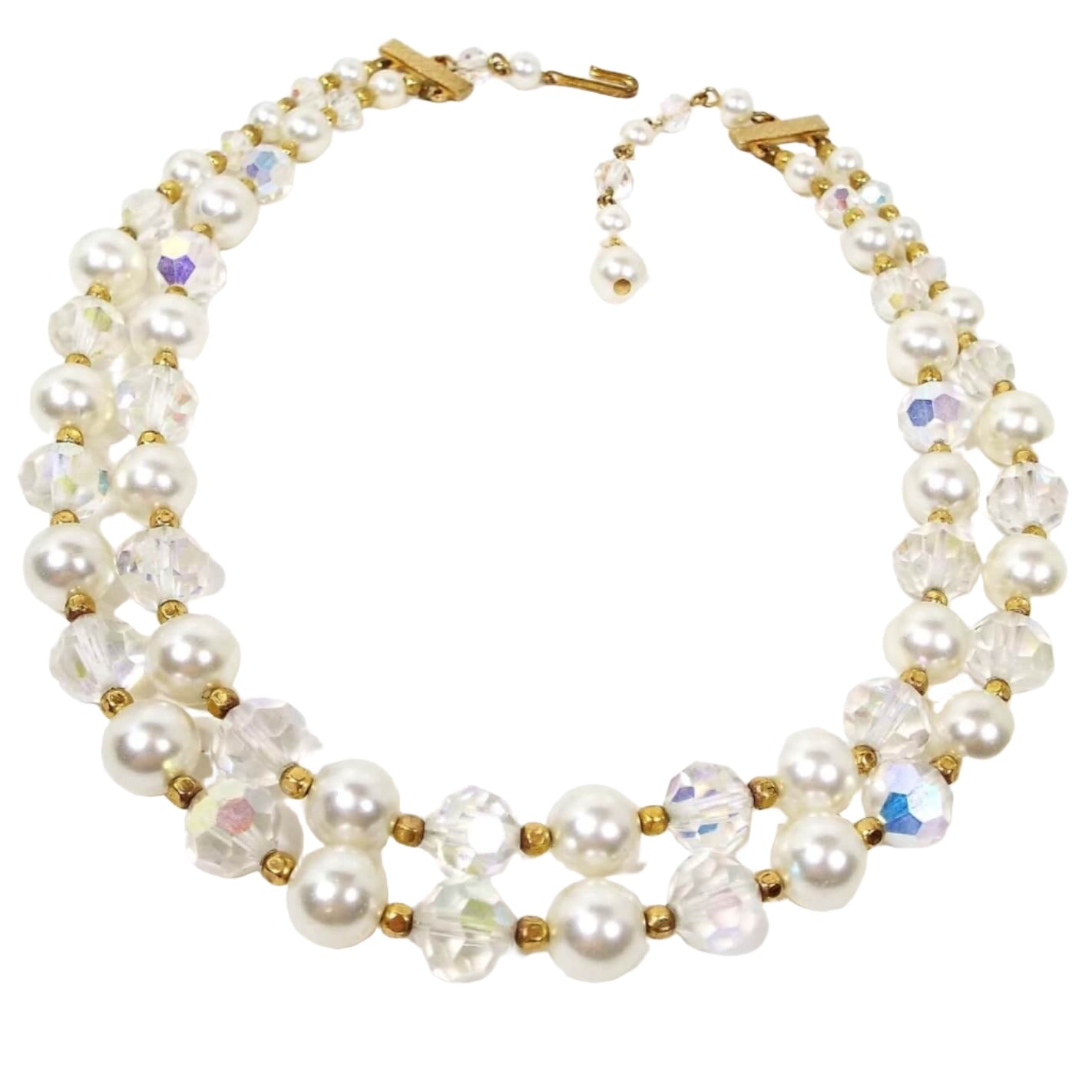 Top view of the Mid Century vintage faux pearl and AB crystal multi strand necklace. There are two strands of beads. Each strand alternates between a plastic imitation pearl and an AB glass crystal bead with small gold tone color beads in between. The hook clasp and other metal components are gold tone in color.