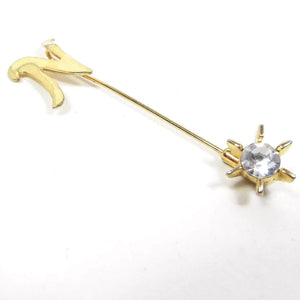 Front view of the Mid Century vintage rhinestone initial stick pin. The metal is gold tone in color. There is a curvy flat letter N at the top and a rhinestone starburst clutch at the bottom.