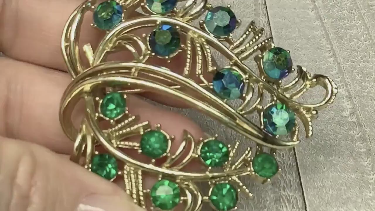 Video of the Mid Century vintage Coro rhinestone leaf brooch. The metal is gold tone in color. There are AB green rhinestones on one side and green rhinestones on the other. The video shows how the rhinestones sparkle.