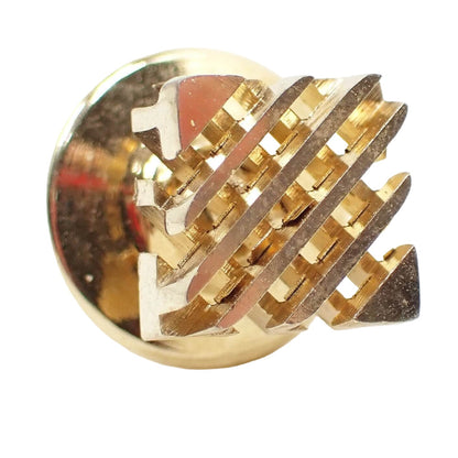 Enlarged angled view of the front of the retro vintage tie tack. It is gold tone in color. The tie tack is square with two layers of cut out diagonal lines. 