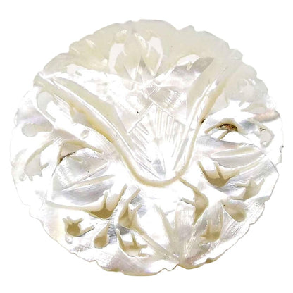 Front view of the Mid Century vintage brooch from Bethlehem. It is mostly round in shape and pearly white in color. The mother of pearl shell is carved with a floral and filigree design. 