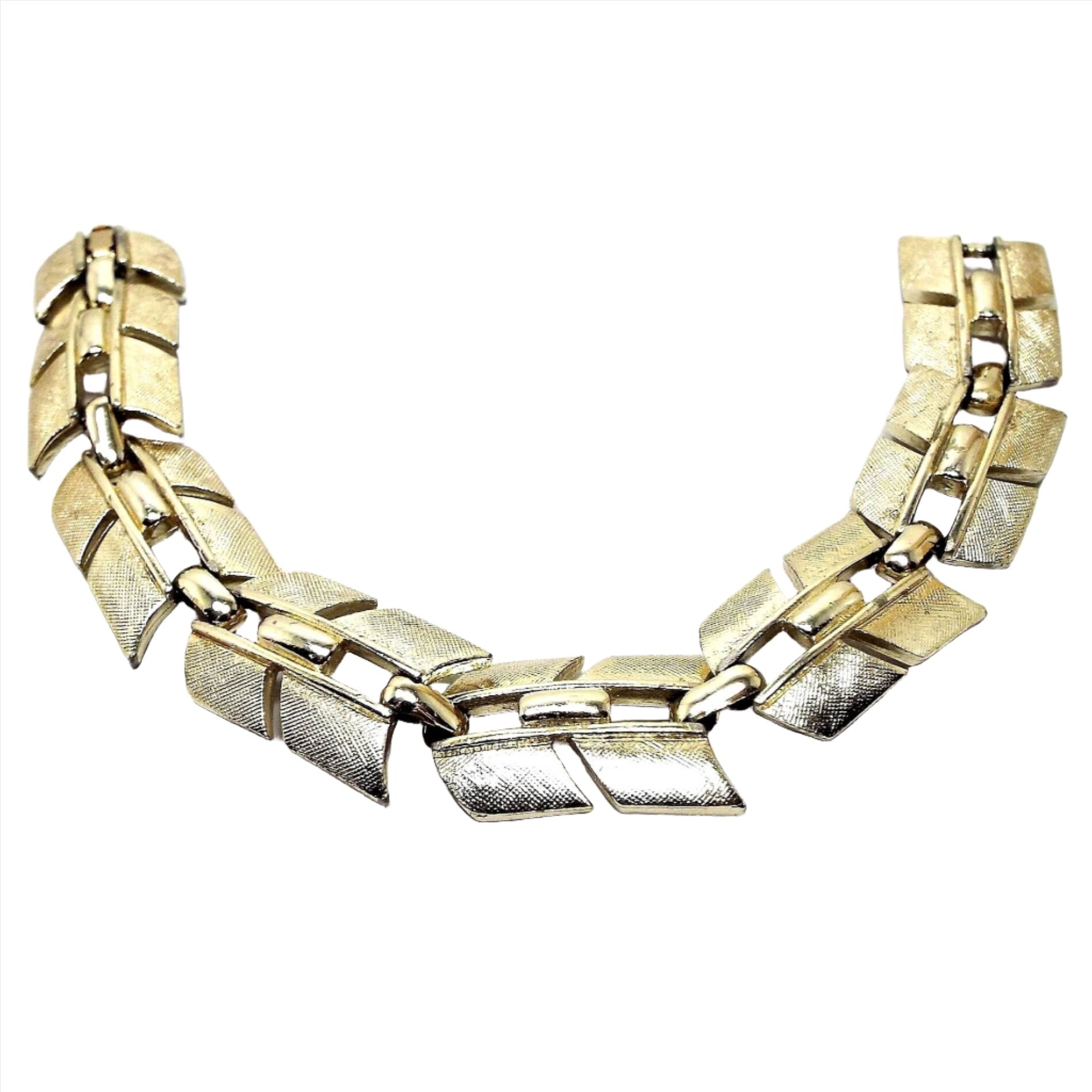 Top view of the retro vintage Sarah Coventry link bracelet. The metal is textured gold tone in color. It link has an angled design. There is a snap lock clasp on the end.