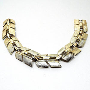 Top view of the retro vintage Sarah Coventry link bracelet. The metal is textured gold tone in color. It link has an angled design. There is a snap lock clasp on the end.