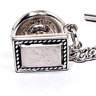 Front view of the Mid Century vintage Hickok rectangle tie tack. It is silver tone in color with a black design around the edge.