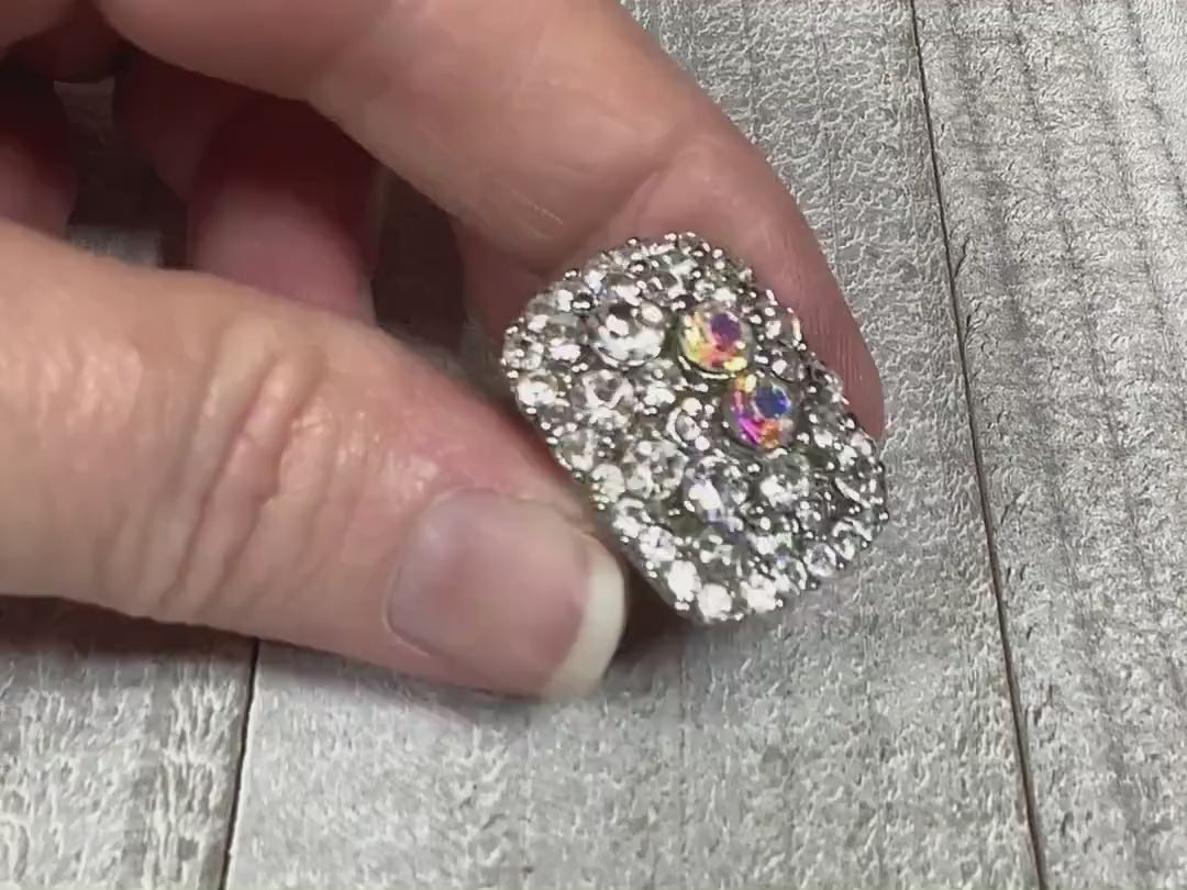 Video of the retro vintage glitzy rhinestone adjustable ring. The top part is rectangle shaped with rounded corners. The top is encrusted with round clear rhinestones and two AB clear rhinestones. The video is showing how all the rhinestones sparkle.