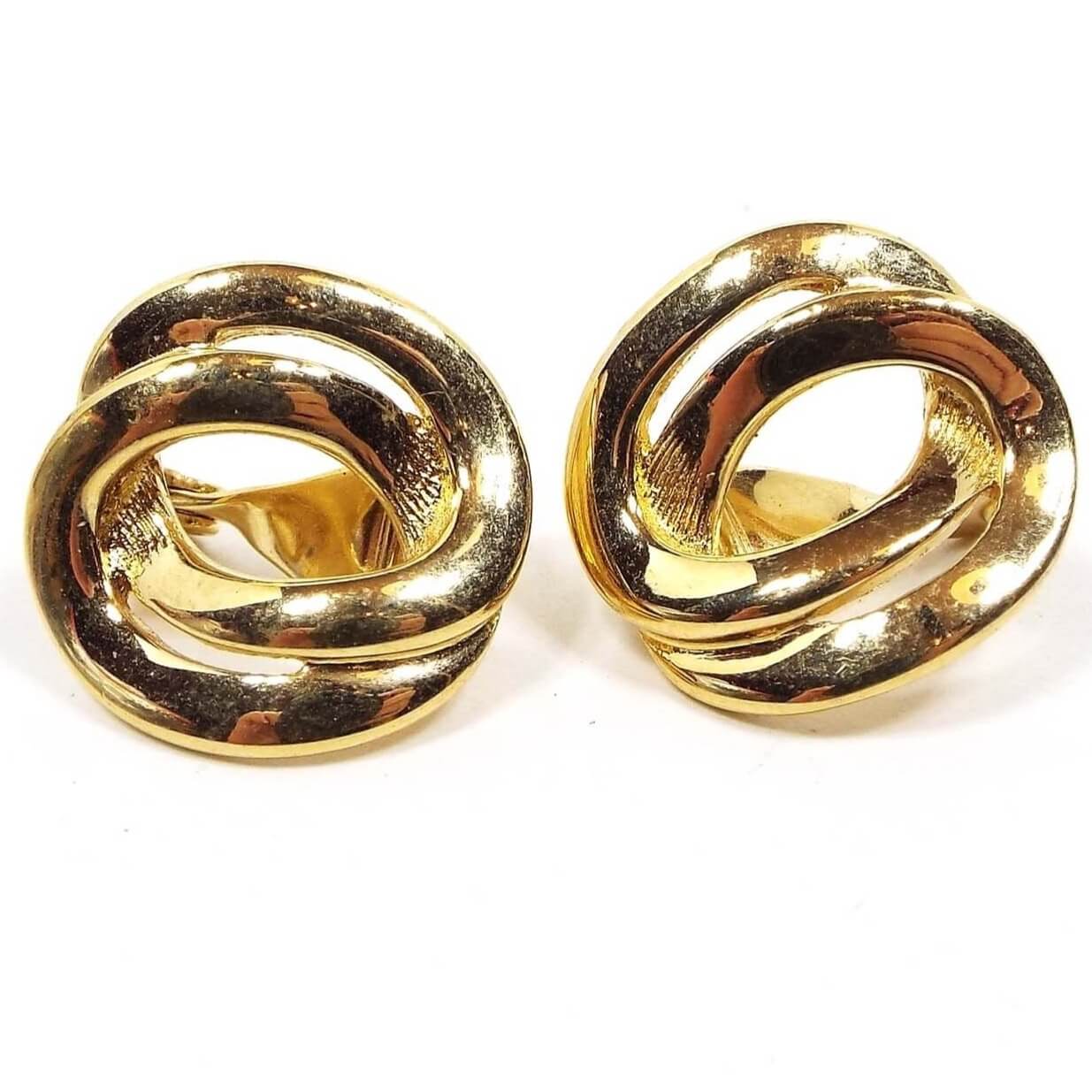 Front view of the Monet retro vintage clip on earrings. The metal is gold tone in color. They are shaped like two intertwined oval links.