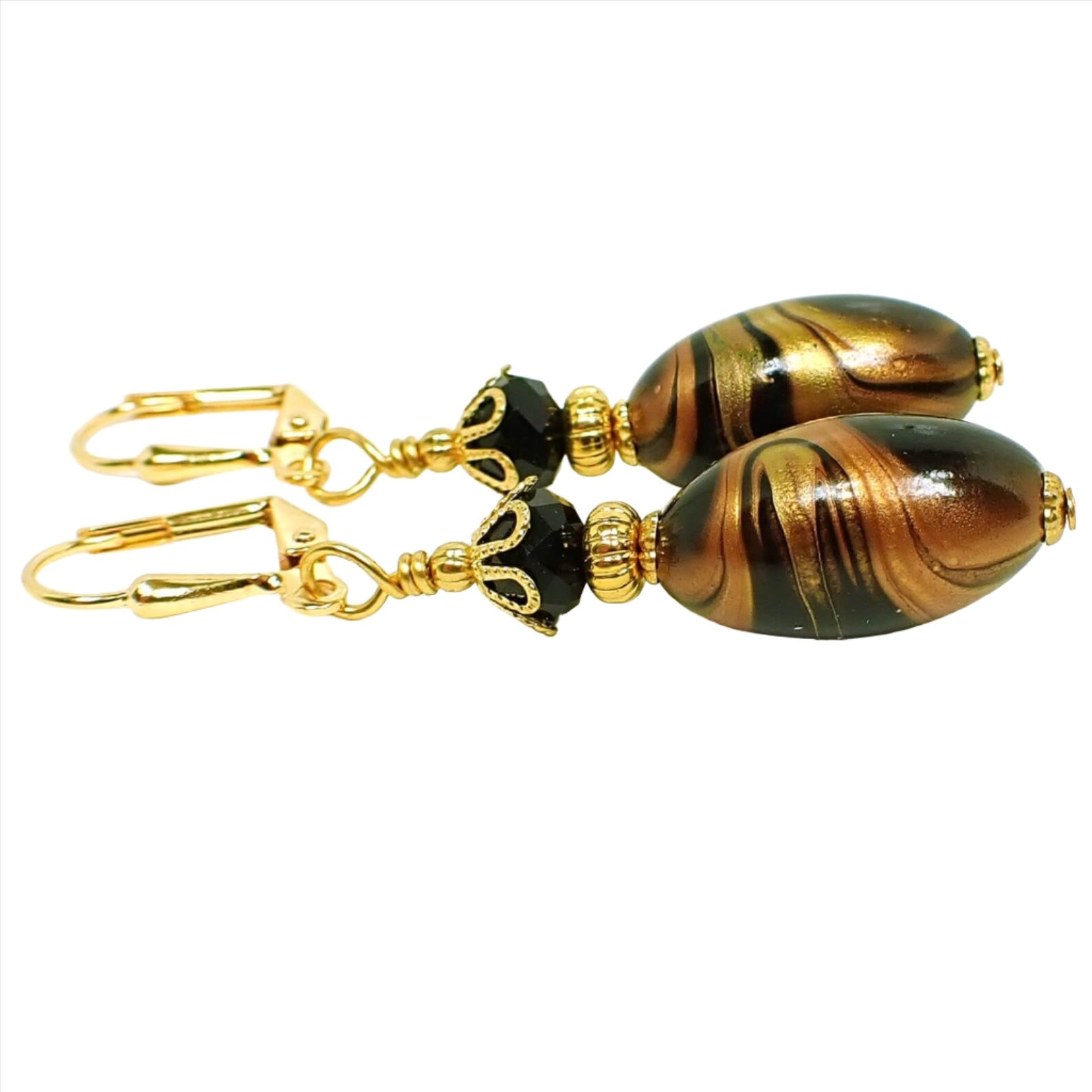 Side view of the handmade lucite earrings. The metal is gold plated in color. There are faceted black glass crystal beads at the top. The bottom lucite beads are black and oval in shape with marbled swirls of metallic gold and copper color. 