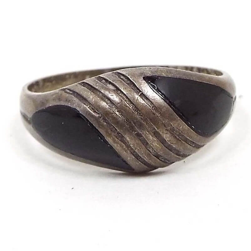 Front view of the retro vintage sterling silver onyx ring. The sterling is darkened to gray from age. The top has a slightly domed rounded design that tapers at the ends. There are four lines etched into the sterling with a curved teardrop shape of inlaid onyx gemstone on either side.